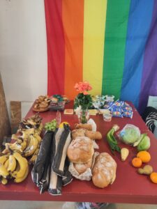 Dumpstered food on a table and pride flag at the back.